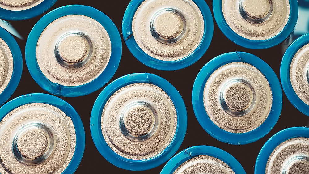 Technicien habilité contrôlant un chargeur de batteries de traction dans un local de charge ventilé d'entrepôt