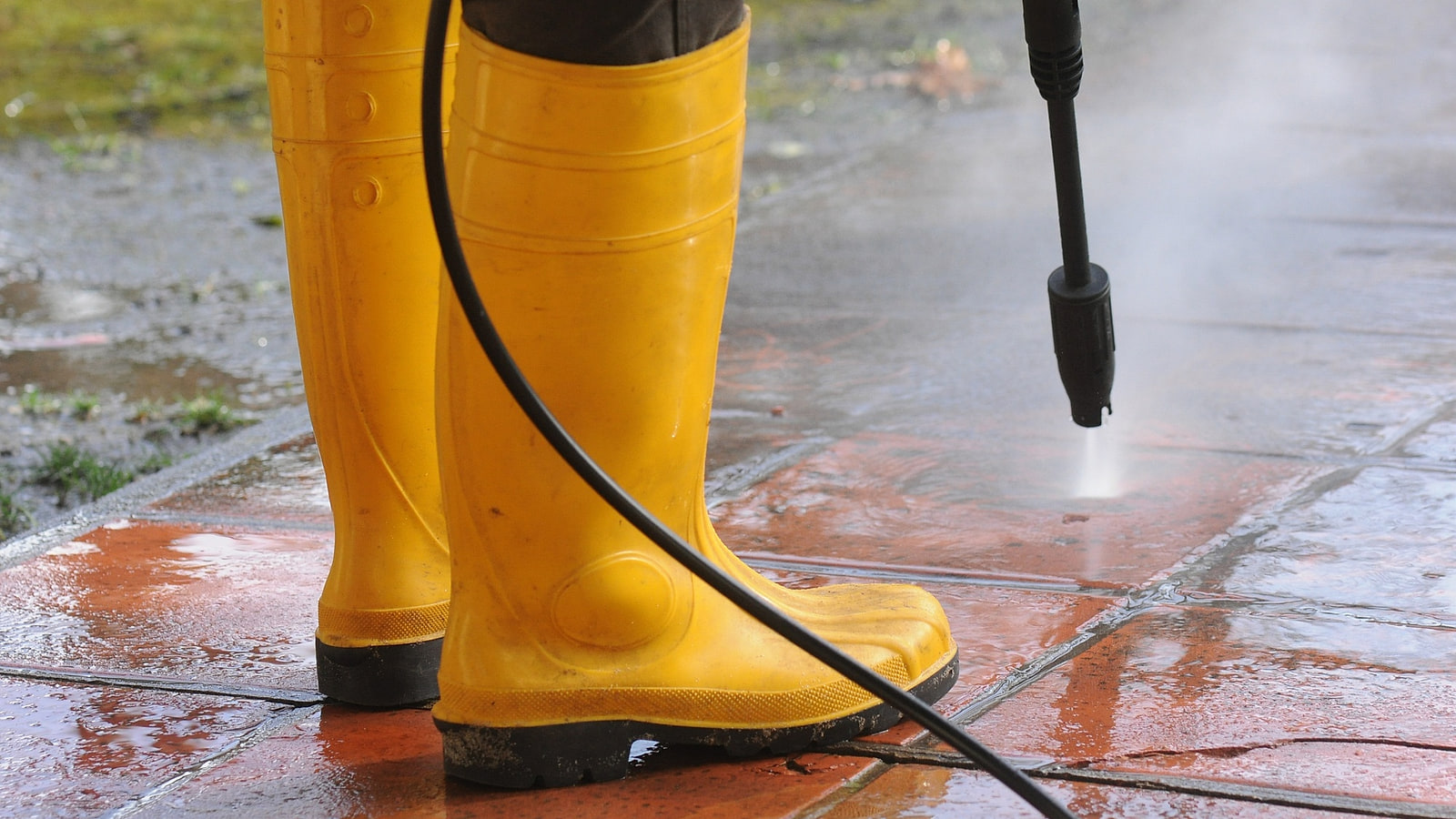 Opérateur dirigeant une lance haute pression dans un regard d'assainissement, hydrocureur en fond