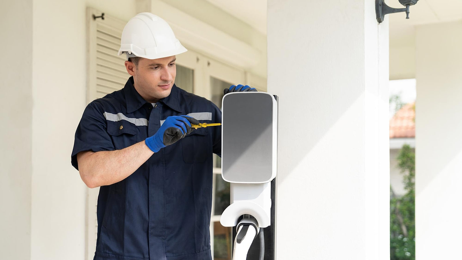 Technicien raccordant une borne de recharge murale dans un parking de copropriété