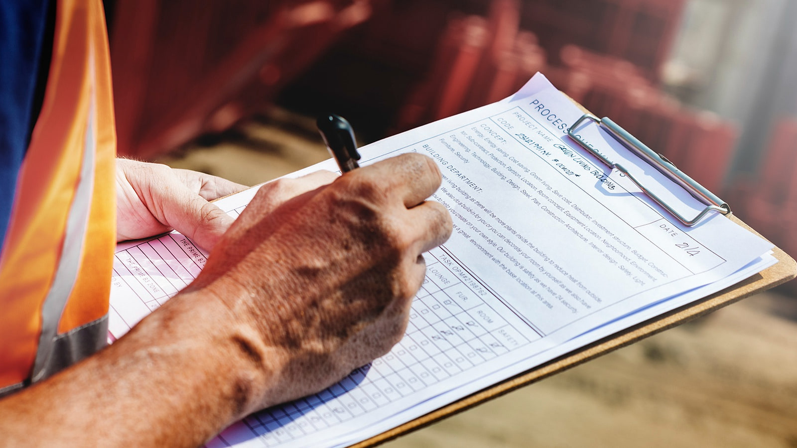 Coordonnateur SPS consignant une observation sur le registre-journal devant un chantier de gros oeuvre en cours