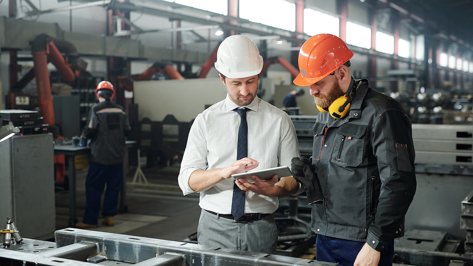 Deux responsables en casque parcourant un site industriel avant travaux
