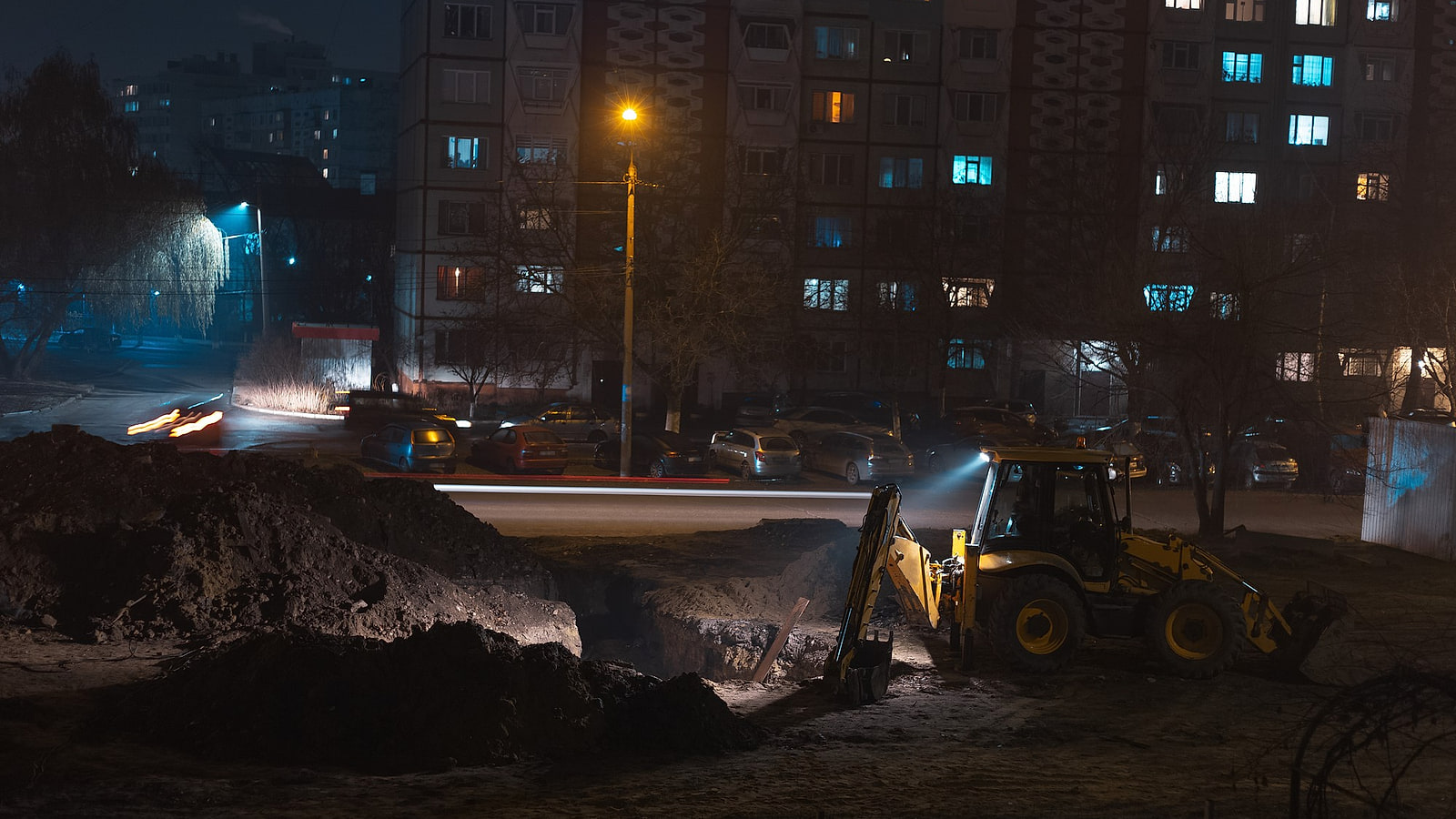Pose d'enrobé de nuit sous projecteurs sur un chantier de voirie, équipe en haute visibilité